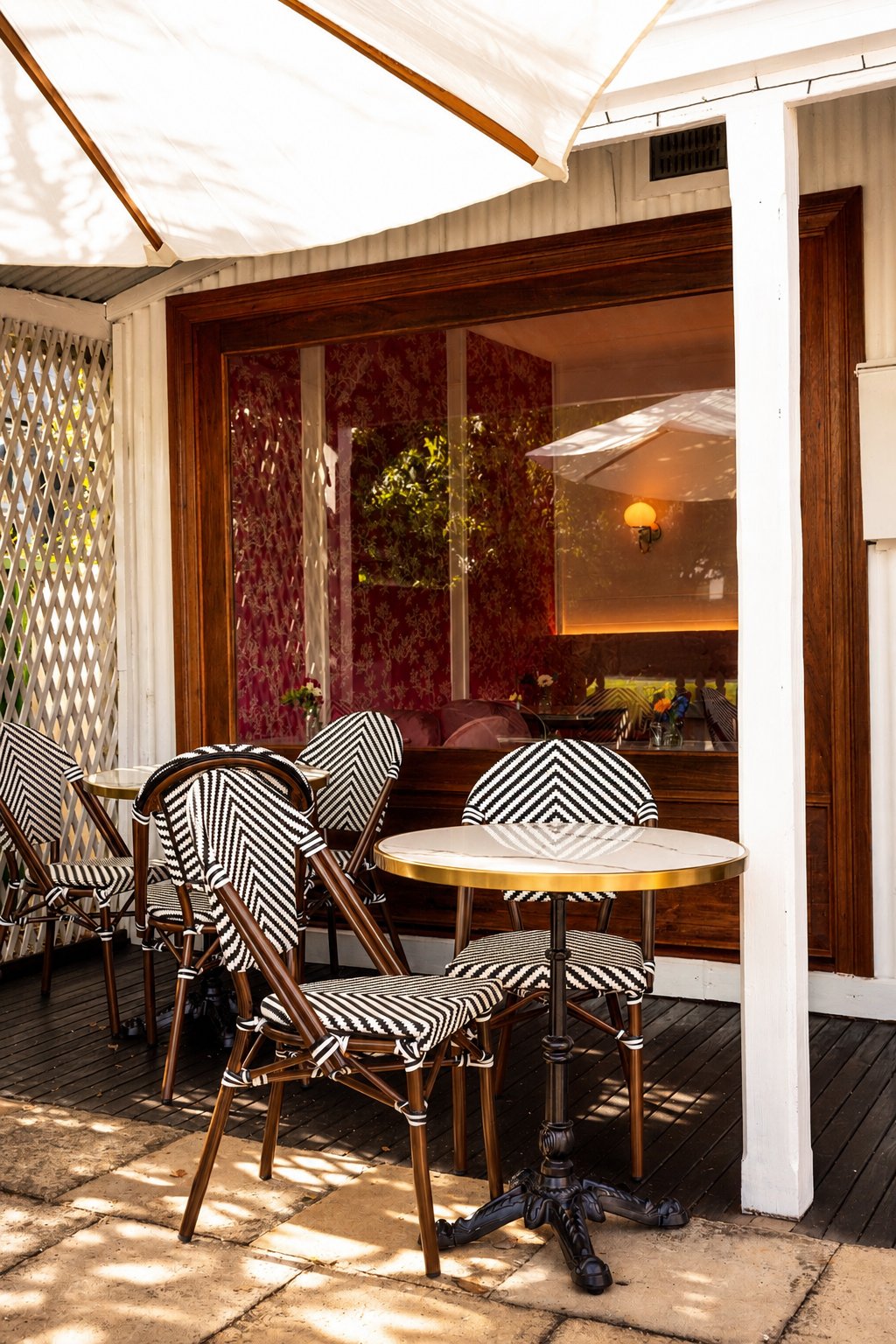 La Pâtisserie Cottage — front verandah with black and white bistro chairs and a marble table
